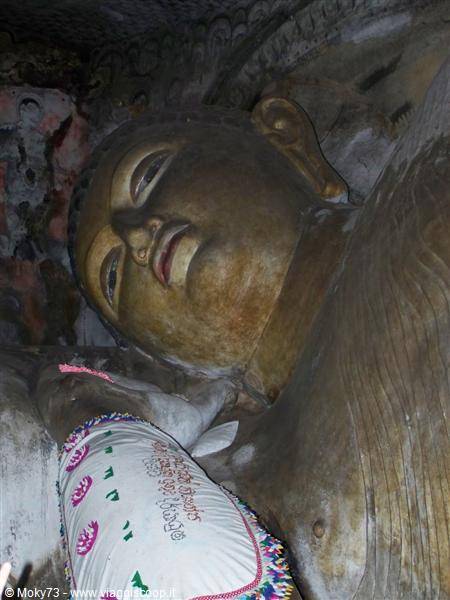 Reclining Buddha inside Dambulla cave temple, golden face in soft light