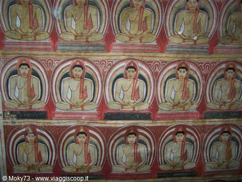 Rows of seated Buddha murals, red and ochre paint on temple wall