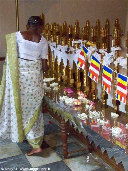 Woman in sari prays among golden stupas and lotus flowers at Temple of the Tooth, Kandy