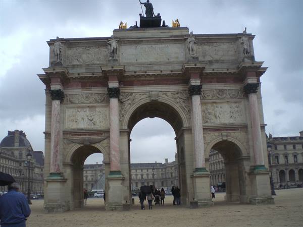 Arc de Triomphe du Carrousel in Paris, marble arch with pedestrians under grey sky