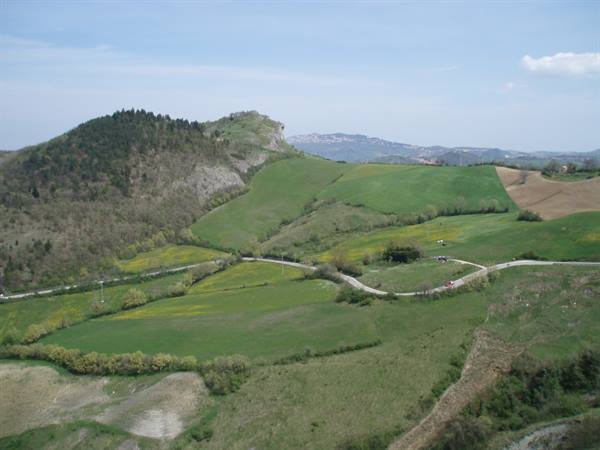 Green rolling hills with country roads and a distant village on the ridge