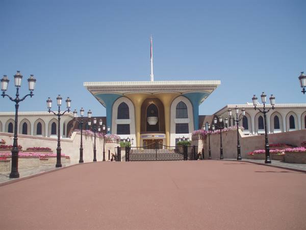 Al Alam Palace in Muscat: colorful facade, red avenue, lampposts and flowers