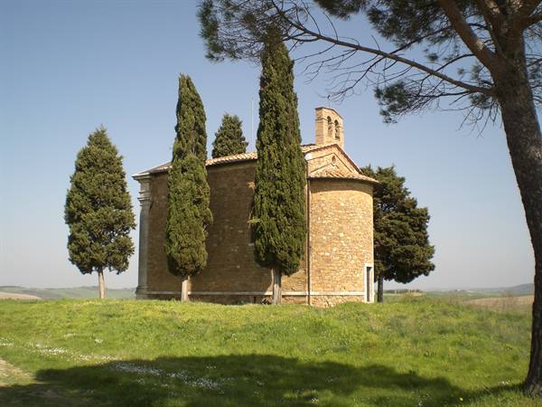 Vitaleta chapel, golden stone among cypresses on a green meadow