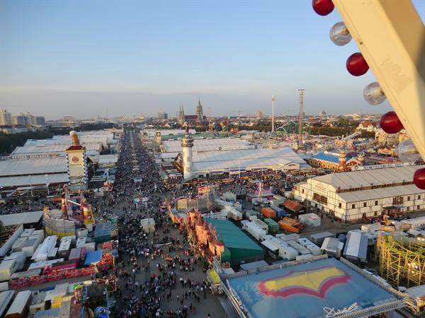 Oktoberfest in Munich: crowds among white beer tents and rides from the Ferris wheel