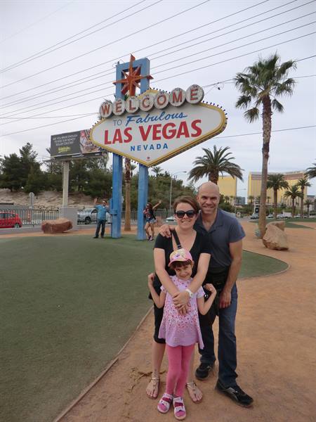 Couple with little girl posing in front of the Welcome to Fabulous Las Vegas sign