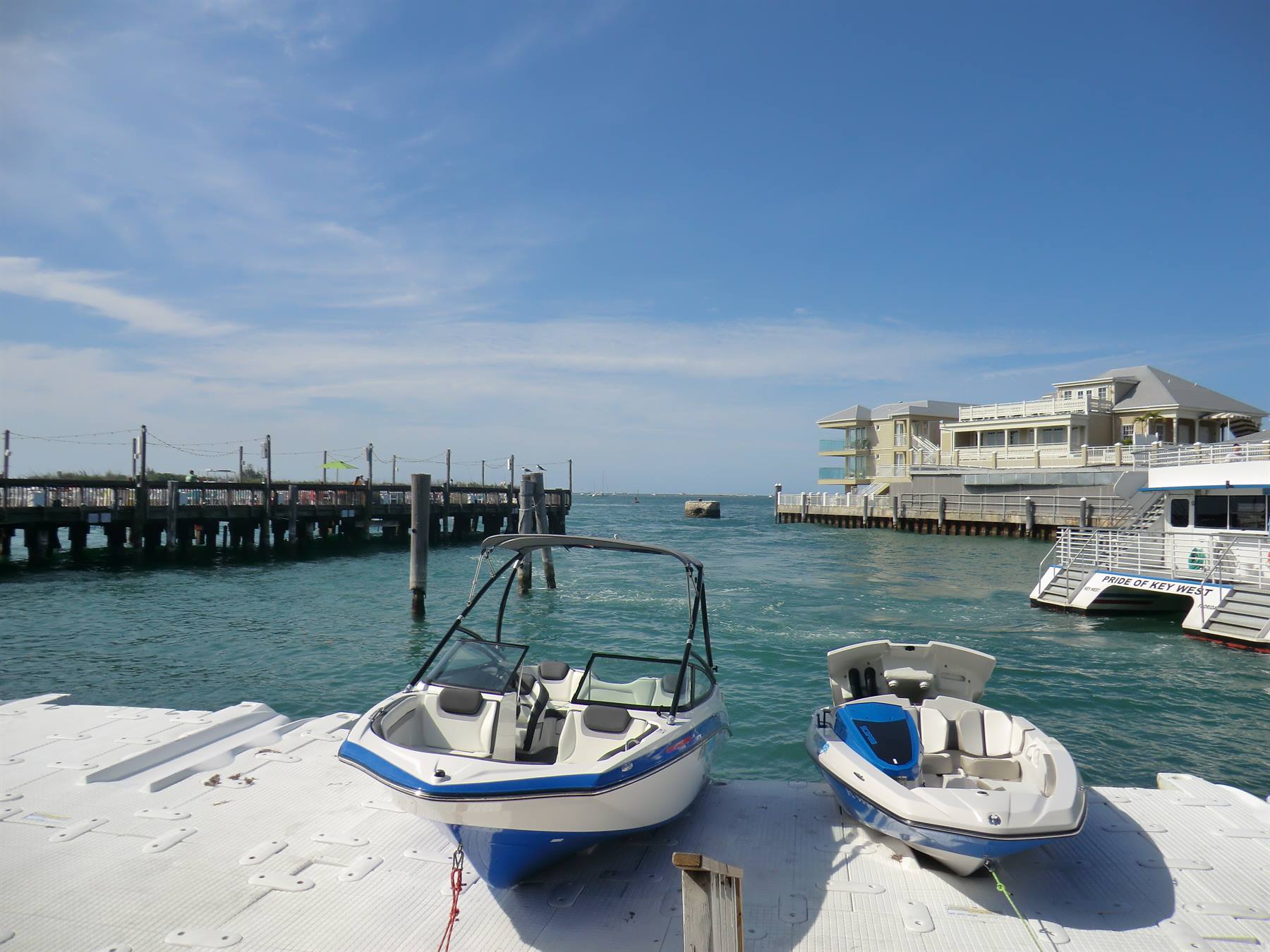 Due barche fermate su pontile bianco, molo di legno e hotel sul mare