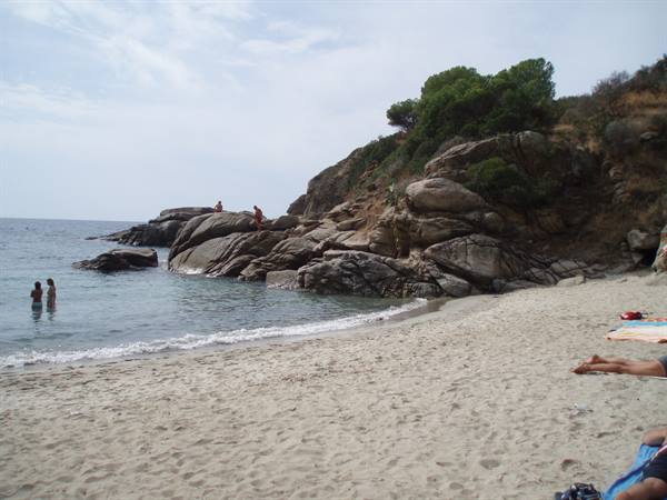 Sandy beach with granite rocks, swimmers in the water and sunbathers