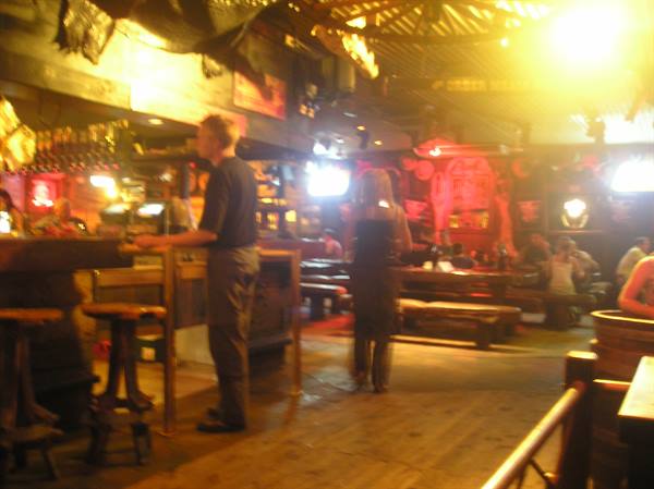 Rustic wooden pub interior, patrons at the bar under warm lights