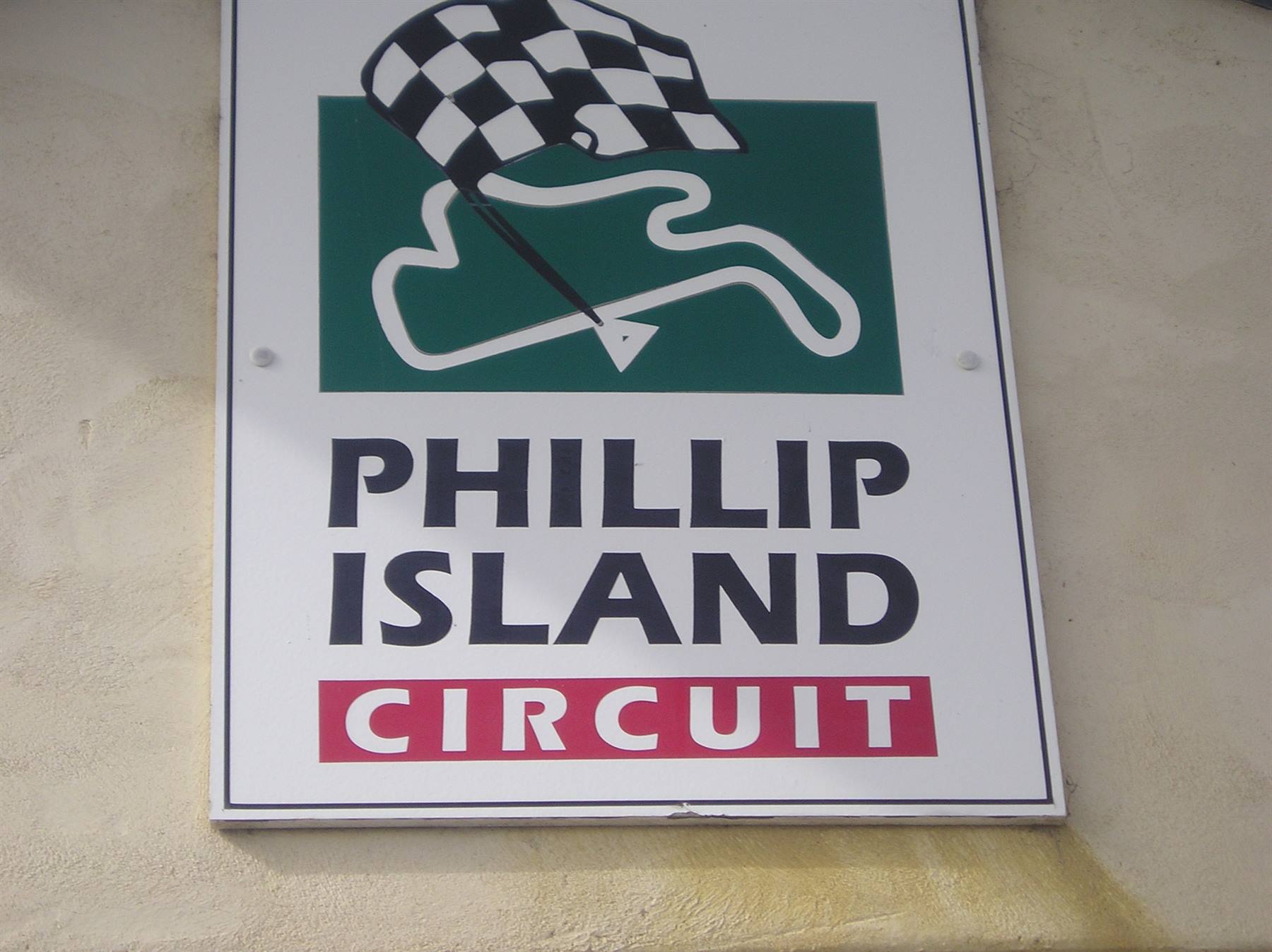 Phillip Island Circuit sign with checkered flag logo on wall