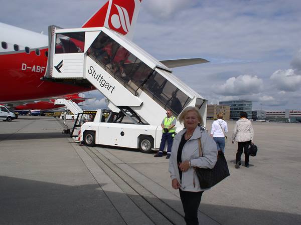 Smiling woman beside mobile boarding stairs and Air Berlin plane at Stuttgart