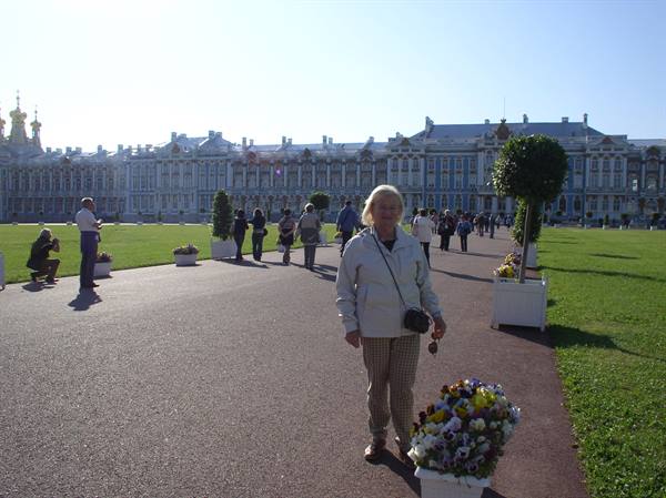Smiling woman beside flowers in front of the Catherine Palace, Tsarskoye Selo