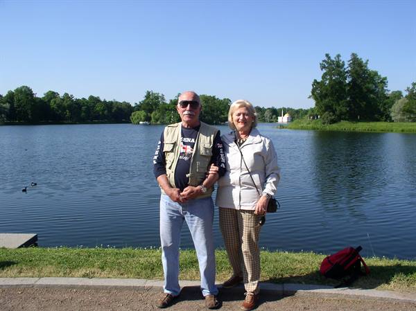 Elderly couple posing together beside a calm lake on a clear day