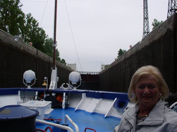 Boat crossing a concrete lock chamber, woman in the foreground