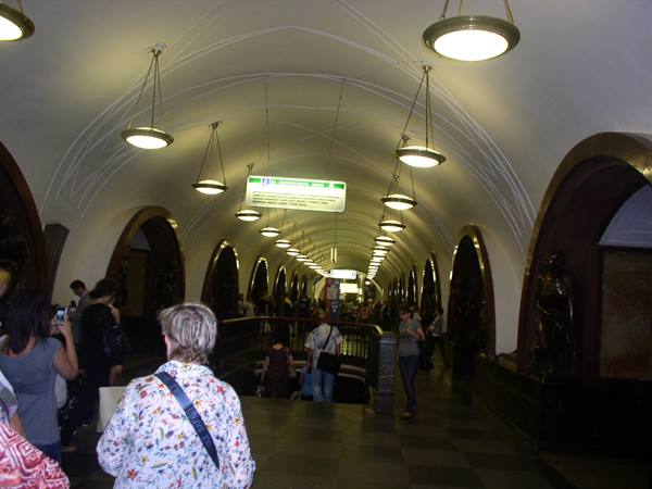 Commuters under the vaulted ceilings of Ploshchad Revolyutsii metro, brass lamps