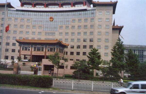 Ministry building in Beijing, traditional Chinese roof, red flag, passing cars