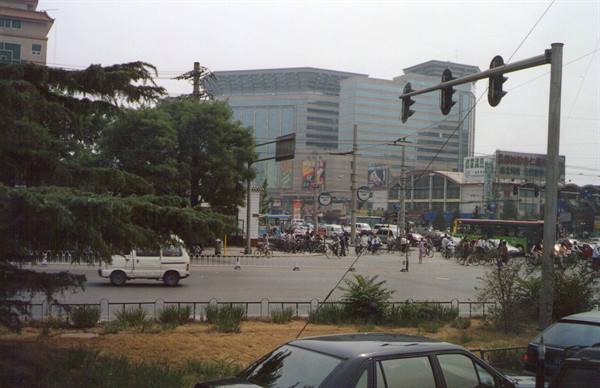 Busy Beijing intersection with traffic, traffic lights and towers under hazy sky