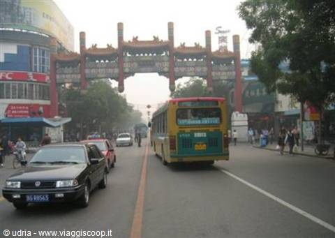 Bus and cars under a red monumental gate in Beijing