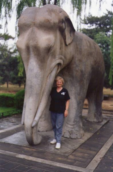 Woman next to a stone elephant statue in a park