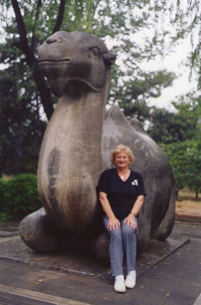 Woman sitting beside a stone camel statue on the Sacred Way, Ming Tombs