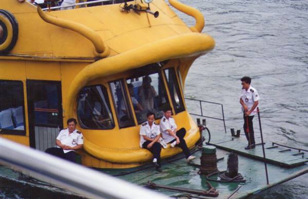 Sailors in white uniforms on a yellow ferry moored on the river