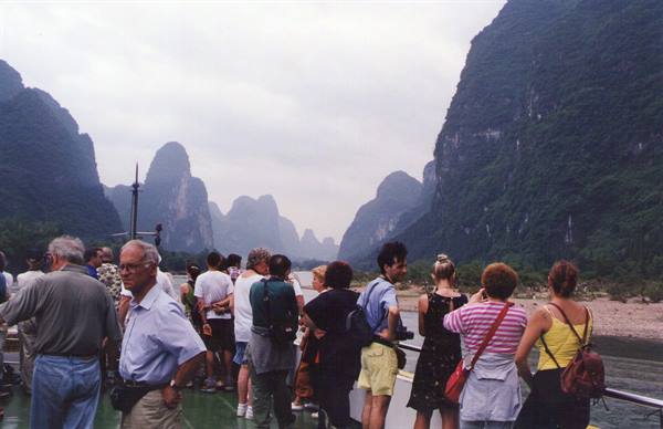 Tourists on a boat deck on the Li River among limestone karst peaks