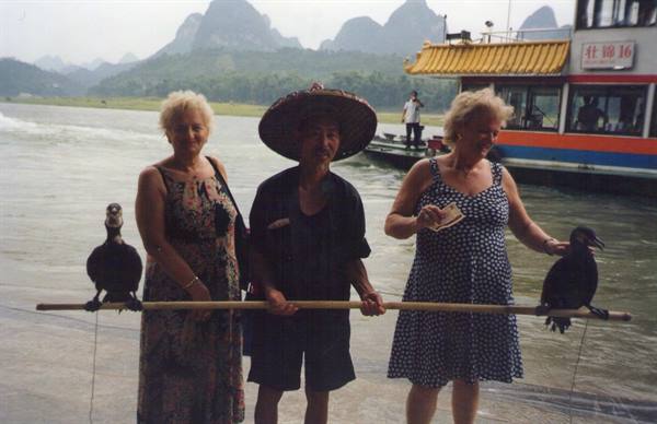 Cormorant fisherman on the Li River with two tourists, tour boat nearby