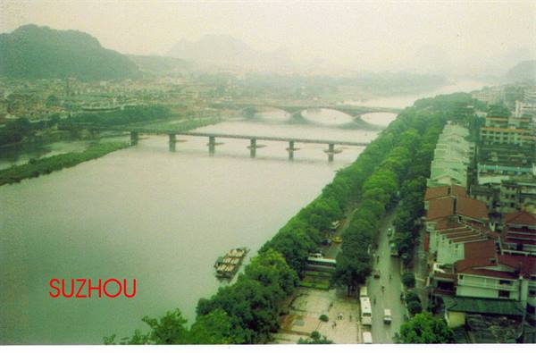 River with bridges and boats among green city buildings, Suzhou
