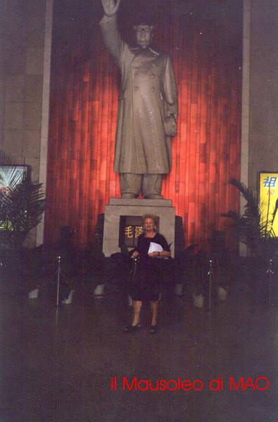 Tourist in front of Mao's raised-arm statue against red backdrop