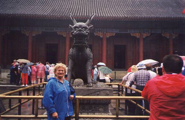 Tourist beside the bronze dragon statue at the Summer Palace in the rain