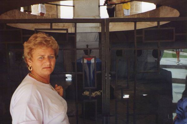 Blonde woman beside a glass door with dark blue stained glass and white flowers