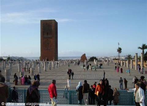 Visitors across the wide stone plaza of the Hassan Tower, unfinished columns and blue sky in Rabat