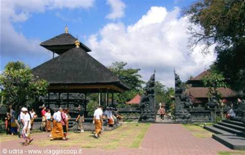 Worshippers in sarongs enter the temple with thatched meru tower and split gateway