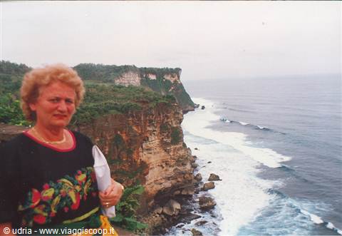 Woman posing at Uluwatu cliffs, ocean waves breaking on rocks below