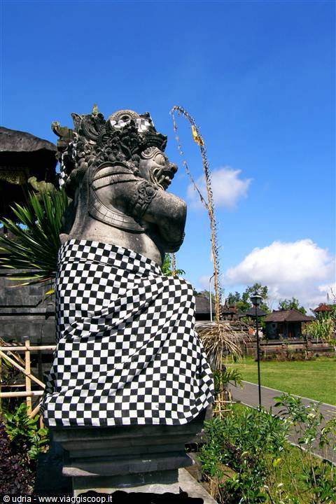 Stone guardian statue wearing checkered poleng cloth at a Balinese temple
