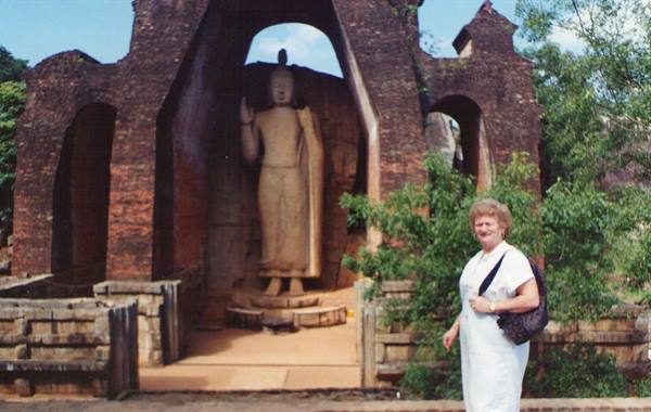 Woman in front of a brick standing Buddha statue at Polonnaruwa