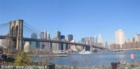 Brooklyn Bridge in New York, blue sky, skyscrapers and boat on East River