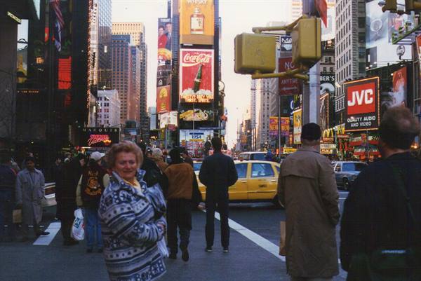 Tourists cross Times Square among Coca-Cola billboards and yellow taxis