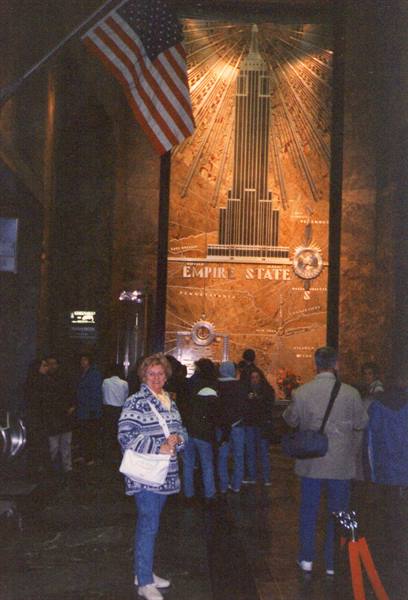Woman in Empire State Building lobby, marble mural and American flag