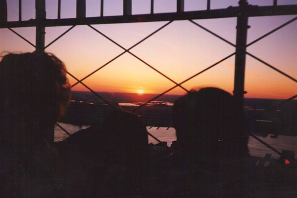 Silhouettes of people behind a metal lattice at sunset