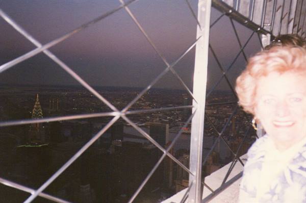 Smiling woman on the Empire State Building terrace behind metal grates