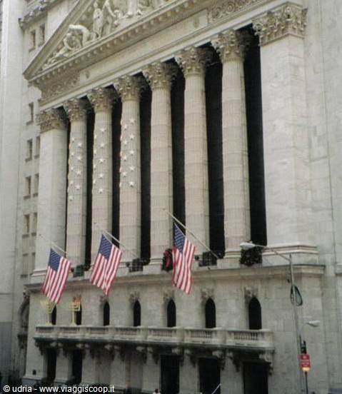Classic stone-column facade with three American flags waving on Wall Street