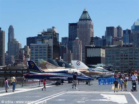 Training jets parked on the Intrepid aircraft carrier deck with Manhattan skyscrapers
