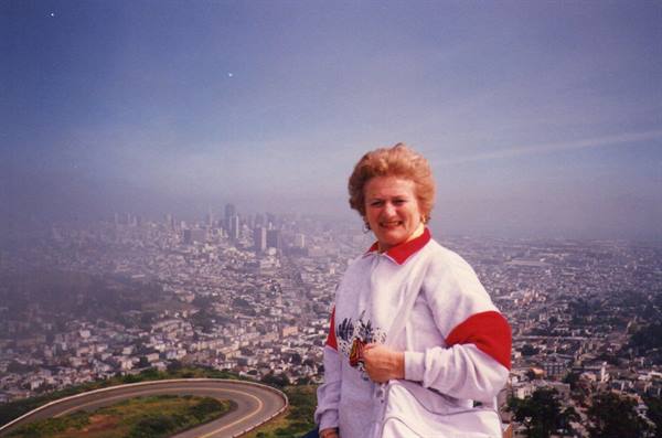 Woman smiling in front of San Francisco skyline from Twin Peaks