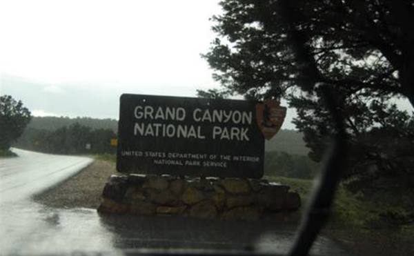 Wooden Grand Canyon National Park sign along the wet roadside in the rain