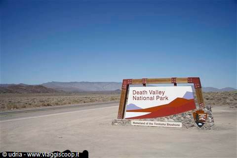 Wooden Death Valley National Park sign on desert sand under blue sky