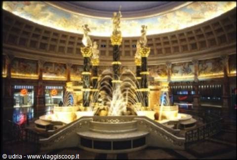Fountain with golden statues under a painted dome, lit atrium
