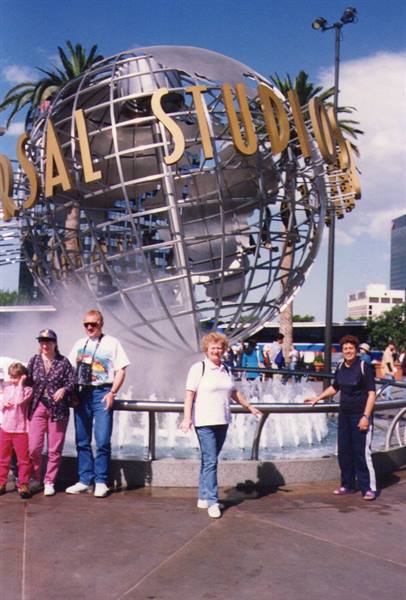 Tourists pose in front of the Universal Studios metal globe fountain