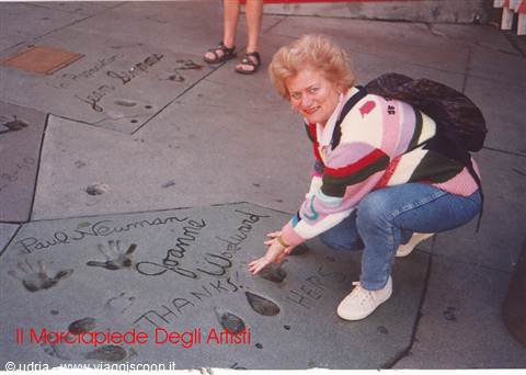 Woman crouching touches handprints in the cement at Hollywood's Walk of Fame