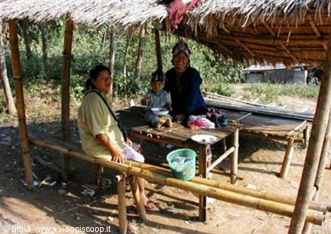 Woman and children under a bamboo hut with thatched roof