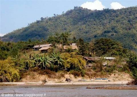 Village with thatched roofs among banana trees, green hills and river